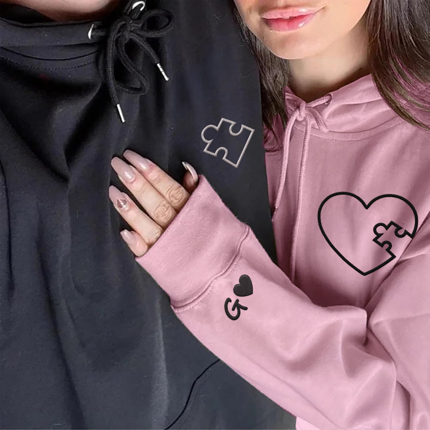 Paar mit schwarzen und rosa Kapuzenpullovern mit Herz-Puzzle-Stickerei und personalisierten Initialen